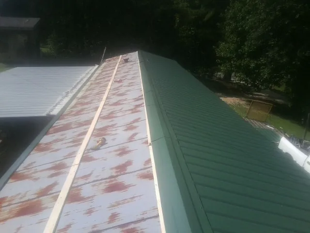 Old rusted panels beside newly installed green metal roofing — Wind Damage Roof Repair by Roofing Brothers in Captiva