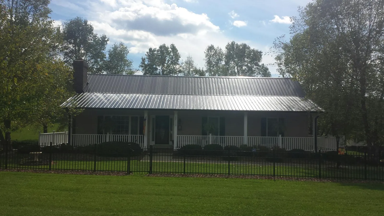 Gray metal roof on a brick ranch with a full width front porch — Gutter Guard Installation work by our crew in Captiva
